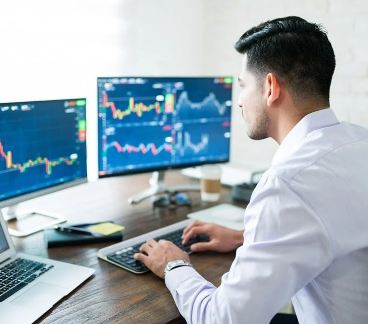 Trader analysant les graphiques sur plusieurs écrans en temps réel